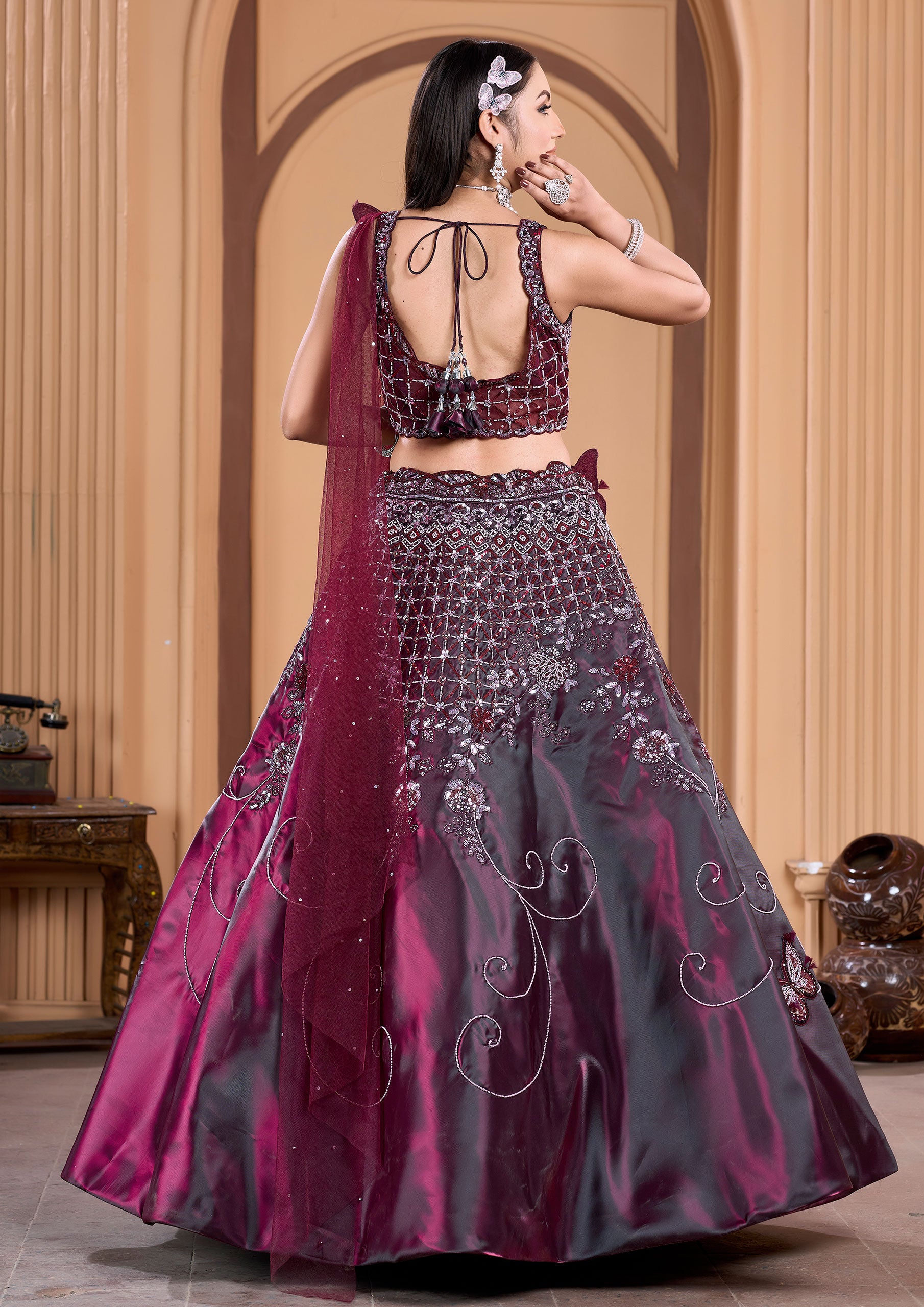 A stunning woman in a wine lehenga and matching blouse, adorned with elegant jewelry.